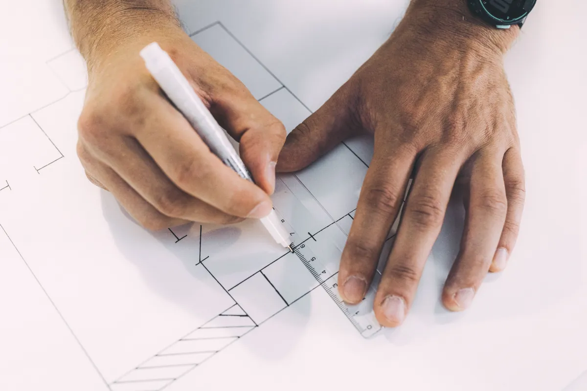 Mains traçant un plan à la règle sur un comptoir