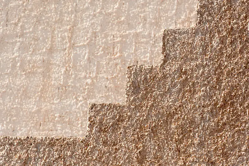 Enduit de façade gratté, teinte ocre, gros plan